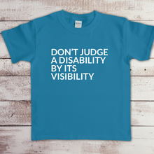 Load image into Gallery viewer, Toddler t-shirt with the phrase “Don’t judge a disability by its visibility” in white vinyl, designed for disability awareness and inclusion. Available in multiple colors, including maroon and blue.
