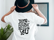 Load image into Gallery viewer, "Tomorrow Needs You" unisex t-shirt by Say Hello Threads, offering a hopeful and motivational message. 988, suicide