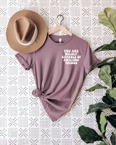 say hello threads shirt with the words you are wildly capable of amazing things on the pocket and on the back of the shirt in large font. 