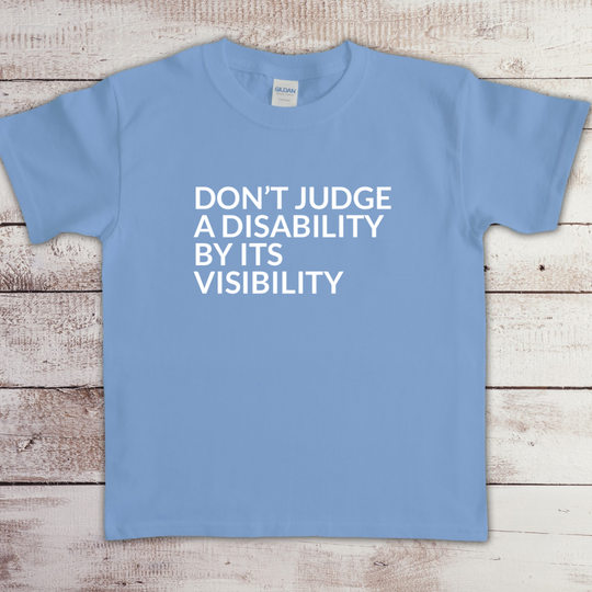 Toddler t-shirt with the phrase “Don’t judge a disability by its visibility” in white vinyl, designed for disability awareness and inclusion. Available in multiple colors, including maroon and blue.