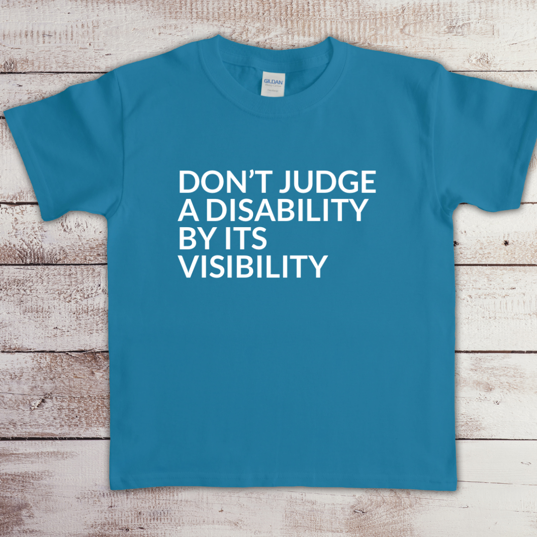 Toddler t-shirt with the phrase “Don’t judge a disability by its visibility” in white vinyl, designed for disability awareness and inclusion. Available in multiple colors, including maroon and blue.